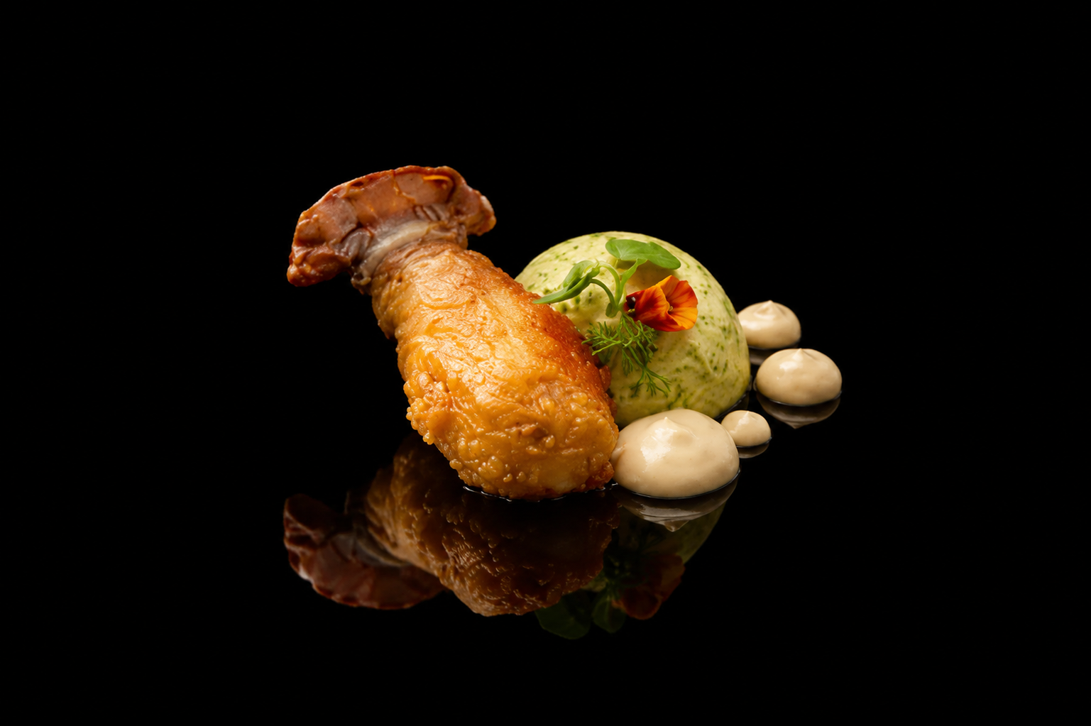 Assiette gastronomique avec un morceau de poisson frit, garnitures crémeuses et légumes, décorée de fleurs