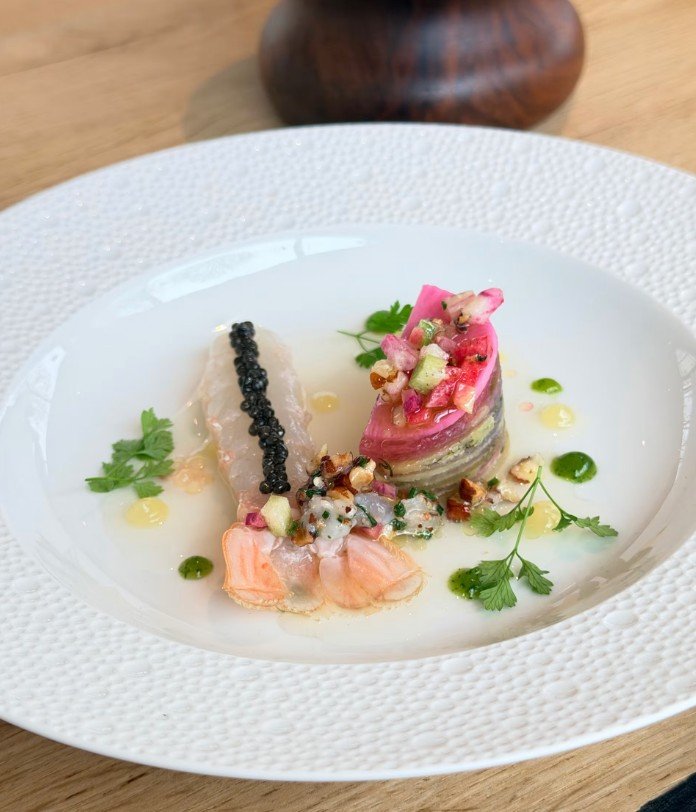 Assiette de poisson avec garnitures colorées, herbes fraîches et sauces variées.