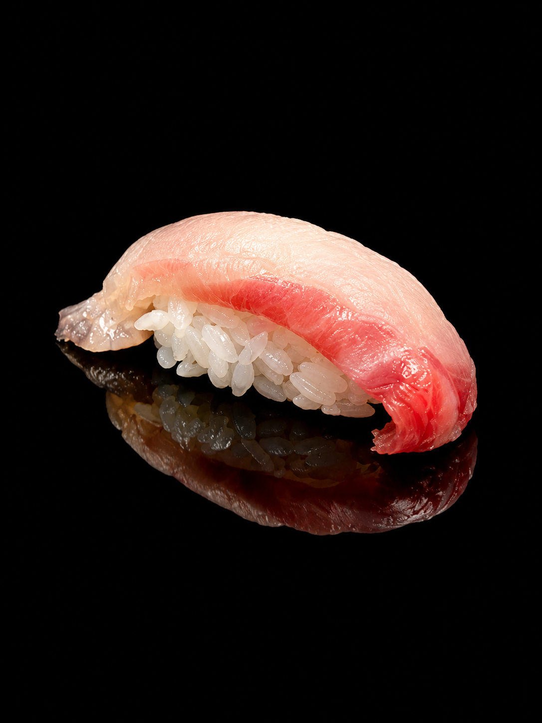 Un morceau de sushi avec du poisson cru et du riz blanc, placé sur un fond noir.