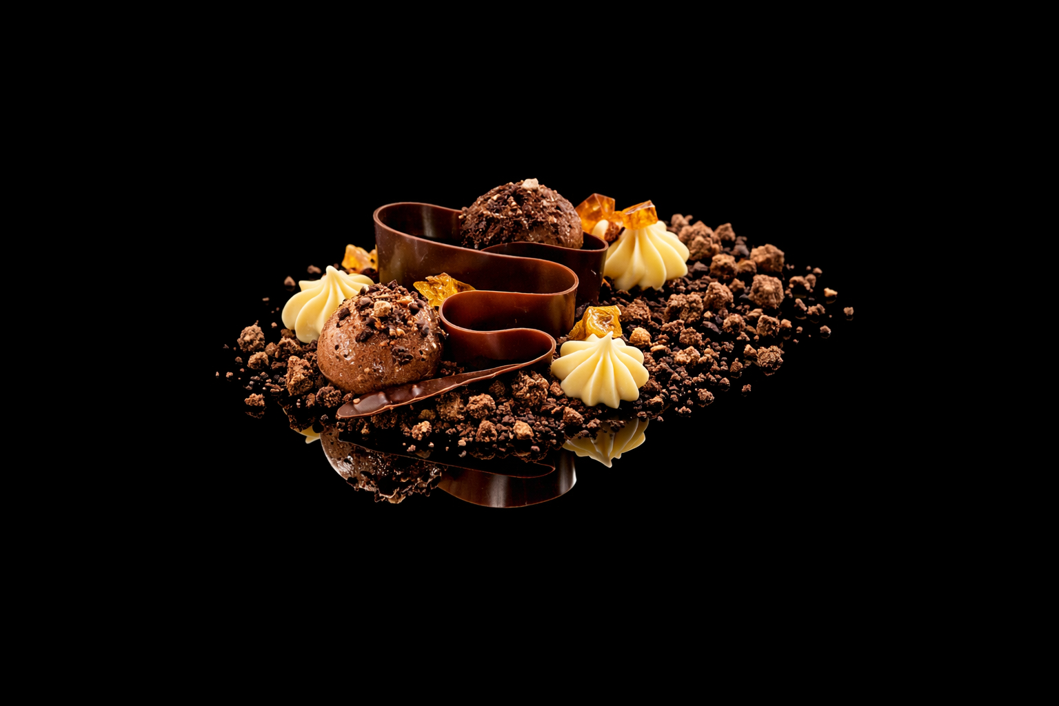 Gâteau au chocolat décoré avec des truffes, des cristaux d'ambre, des coques en chocolat blanc, des miettes de chocolat et une feuille de chocolat