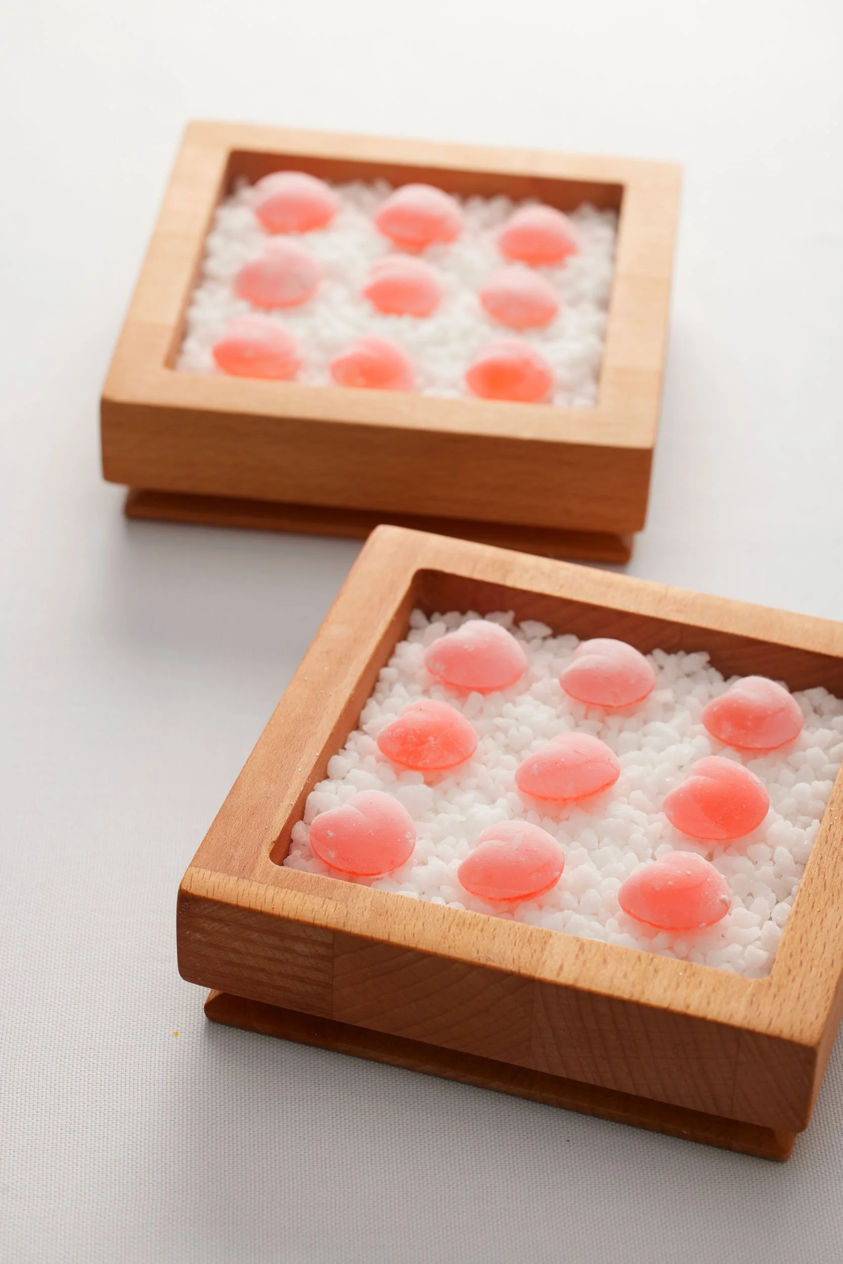 Deux boîtes en bois contenant des chandelles parfumées en forme de coquillage sur du sel de mer