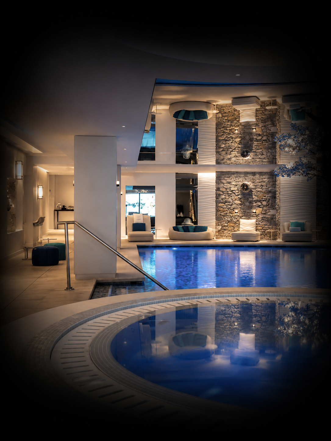 Piscine intérieure dans un espace de luxe, avec des murs en pierre et des chaises confortables avec coussins, éclairage doux et ambiance relaxante.