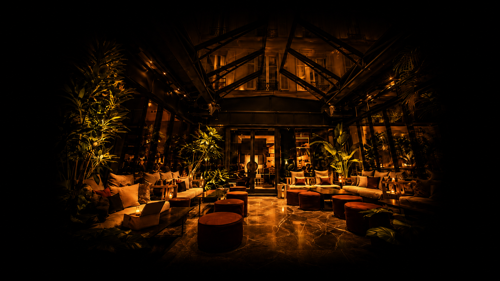 Salon lounge avec canapés, poufs, plantes vertes, éclairage chaud dans un espace élégant et cosy.