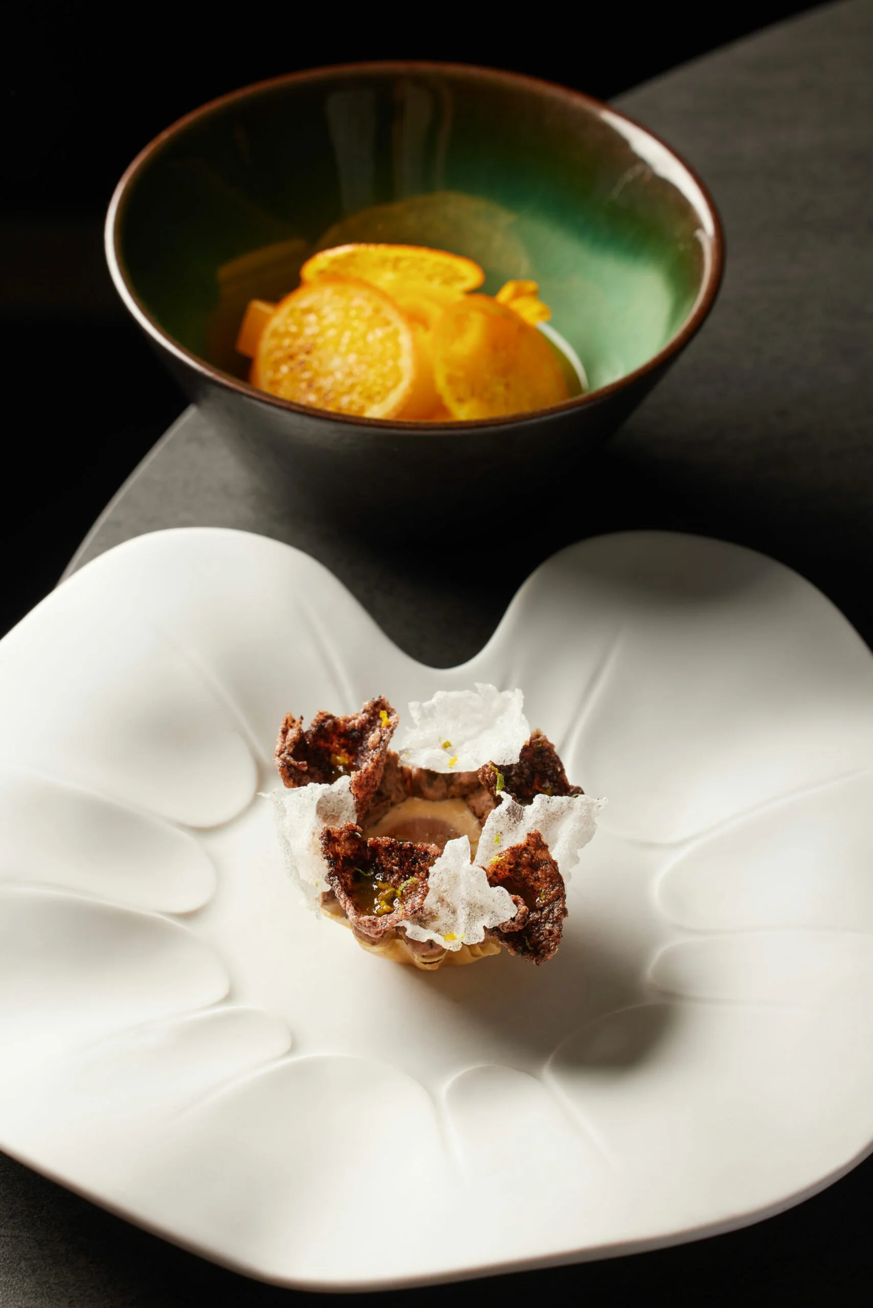 Dessert avec des morceaux de chocolat et des cocons de caramel, accompagné de tranches d'orange dans un bol