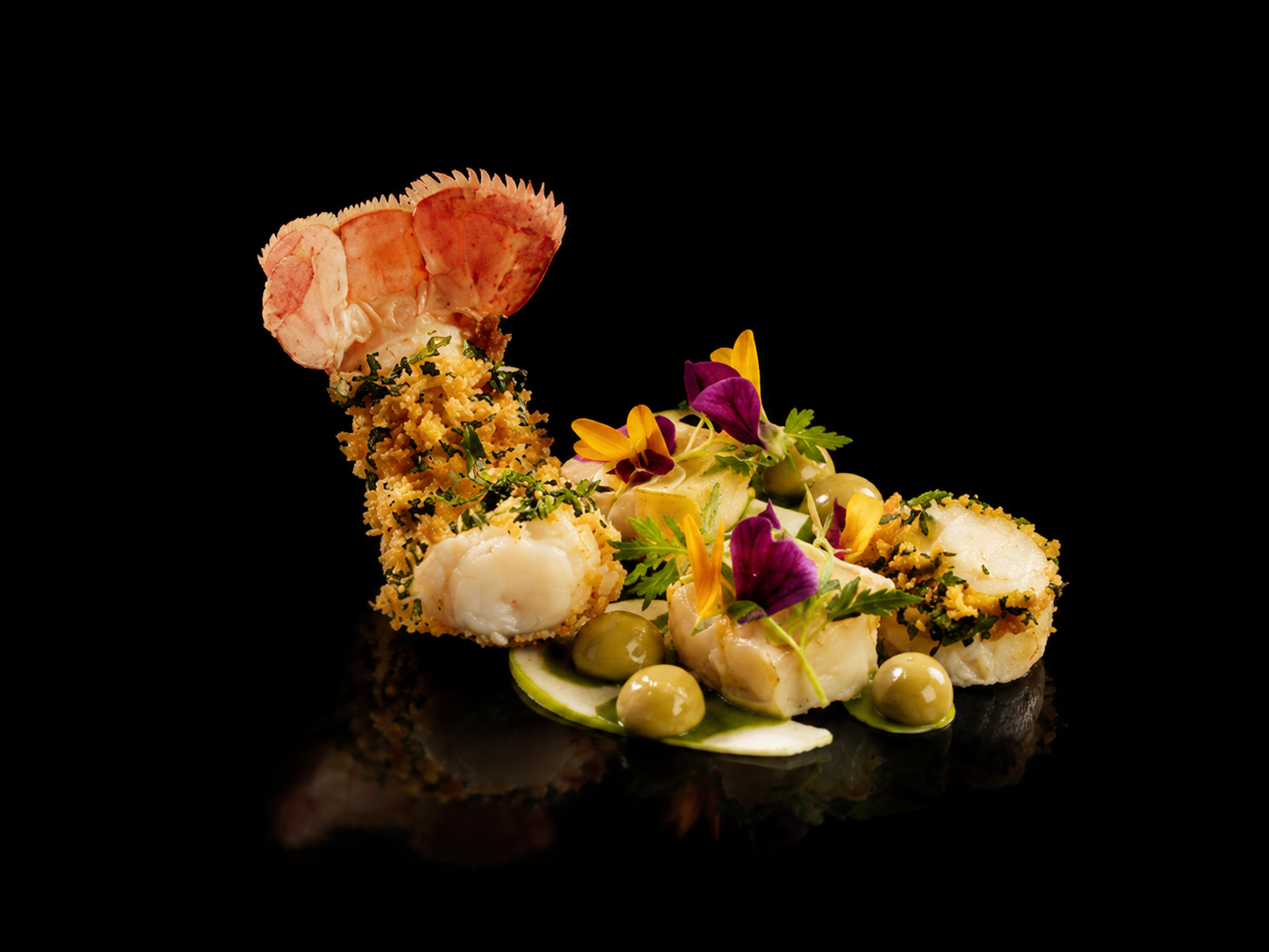 Assiette gastronomique avec divers éléments de poisson, garnitures, herbes et fleurs comestibles, sur fond noir.