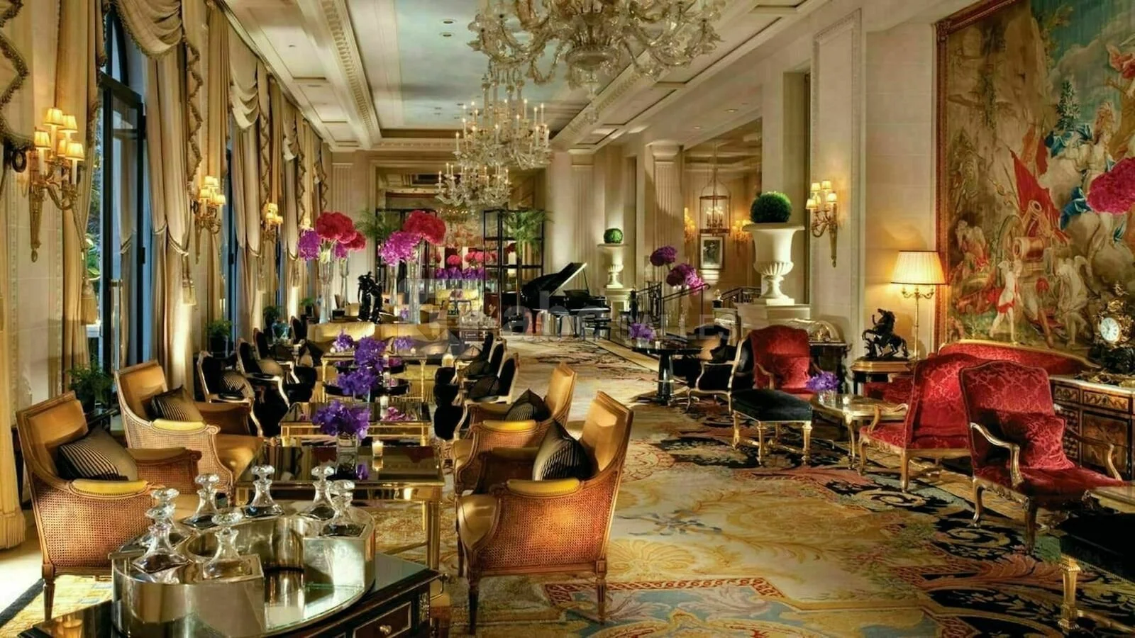 Luxueuse salle de séjour avec mobilier élégant, chandeliers, tapis colorés, grandes fenêtres avec rideaux en tissu riche, décorations florales, pianos, lampes et œuvres d'art mural.