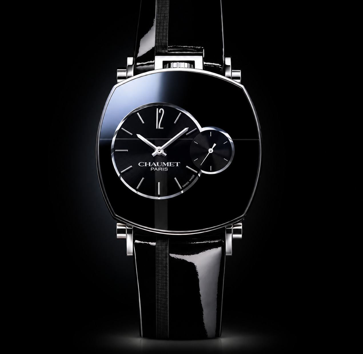 Montre de luxe noire avec deux cadrans, un grand et un petit, la marque 'Chaumet Paris' inscrite sur le grand cadran, contre un fond noir avec des reflets lumineux.