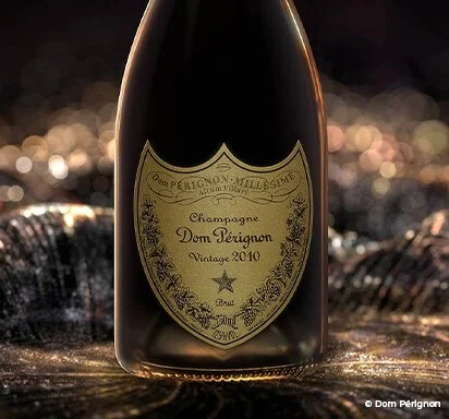 Bouteille de champagne Dom Pérignon vintage 2010 tendue sur une surface brillante avec des reflets lumineux en arrière-plan.
