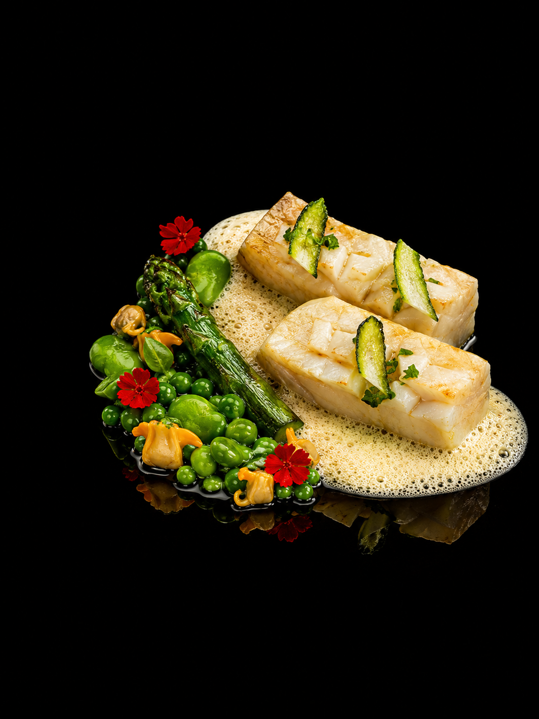 Filet de poisson blanc cuit, garniture de courgettes, accompagnements de céleri, petits pois, champignons, avec des fleurs rouges, présenté sur une sauce mousseuse, fond noir