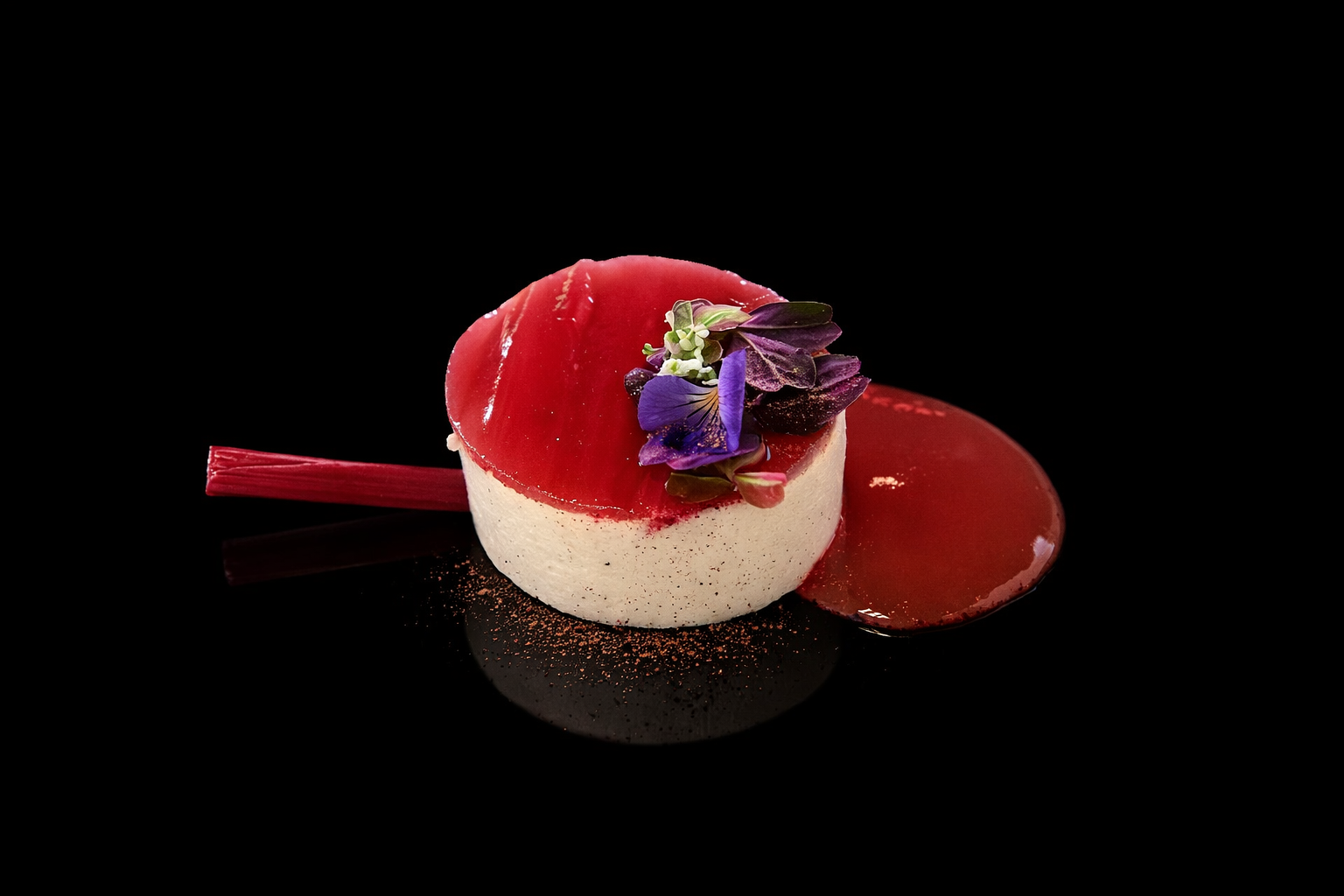 Dessert sophistiqué avec un cercle de mousse blanche, gelée rouge sur le dessus, fleurs comestibles violettes et vertes, et une sauce rouge accompagnant.