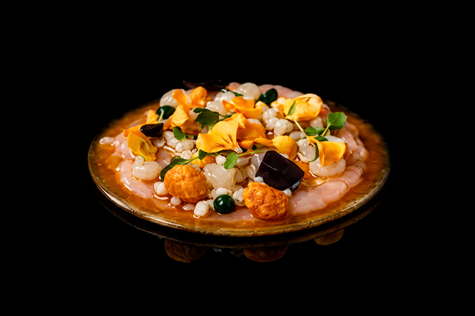 Assiette de ceviche avec poisson, œufs de tapioca, fleurs d'hibiscus, plantes verts, et légumes en sauce