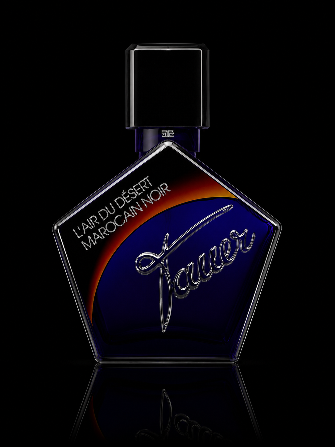 Flacon de parfum de forme géométrique avec le nom 'Jaué' en relief et une étiquette indiquant 'L'air du désert Marocain noir' sur un fond noir