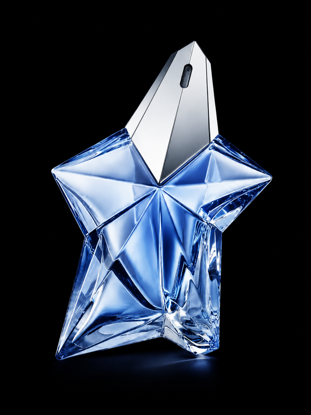 Flacon de parfum en forme d'étoile en verre translucide avec une bouteille d'argent en haut, sur fond noir.