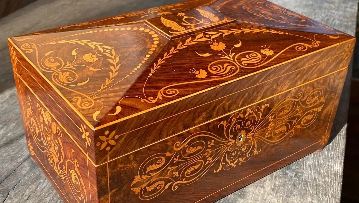 Boîte en bois ornée de motifs floraux et décoratifs en bois clair incrustés sur une surface en bois foncé.