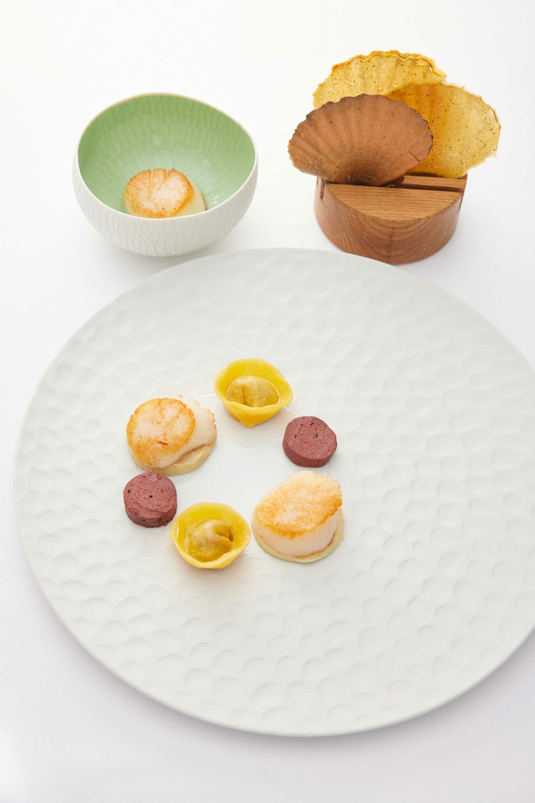 Assiette avec plusieurs petits amuse-bouches, bols avec chips, fond blanc.