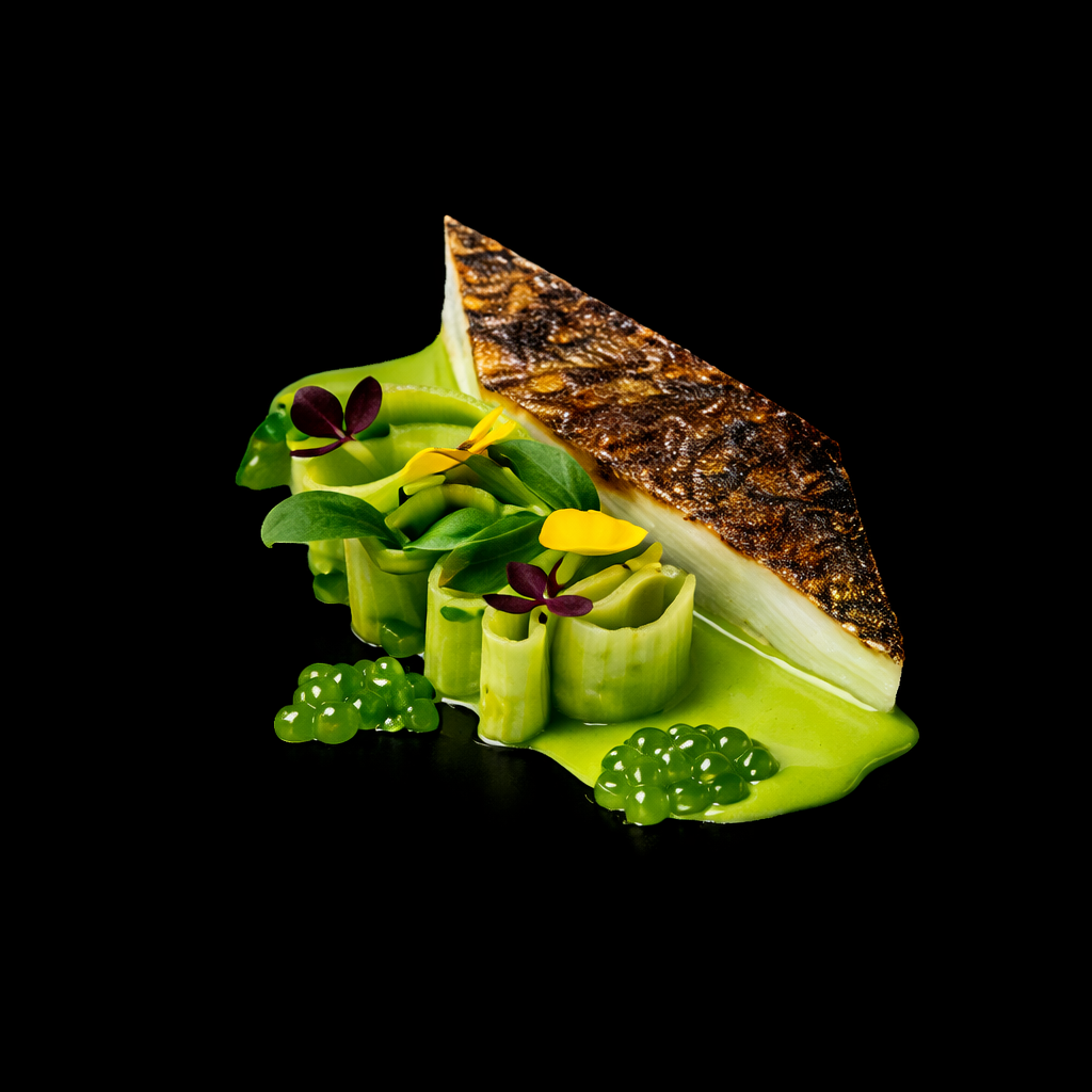 Assiette de poisson grillé avec légumes verts et garnitures décoratives sur un fond noir.