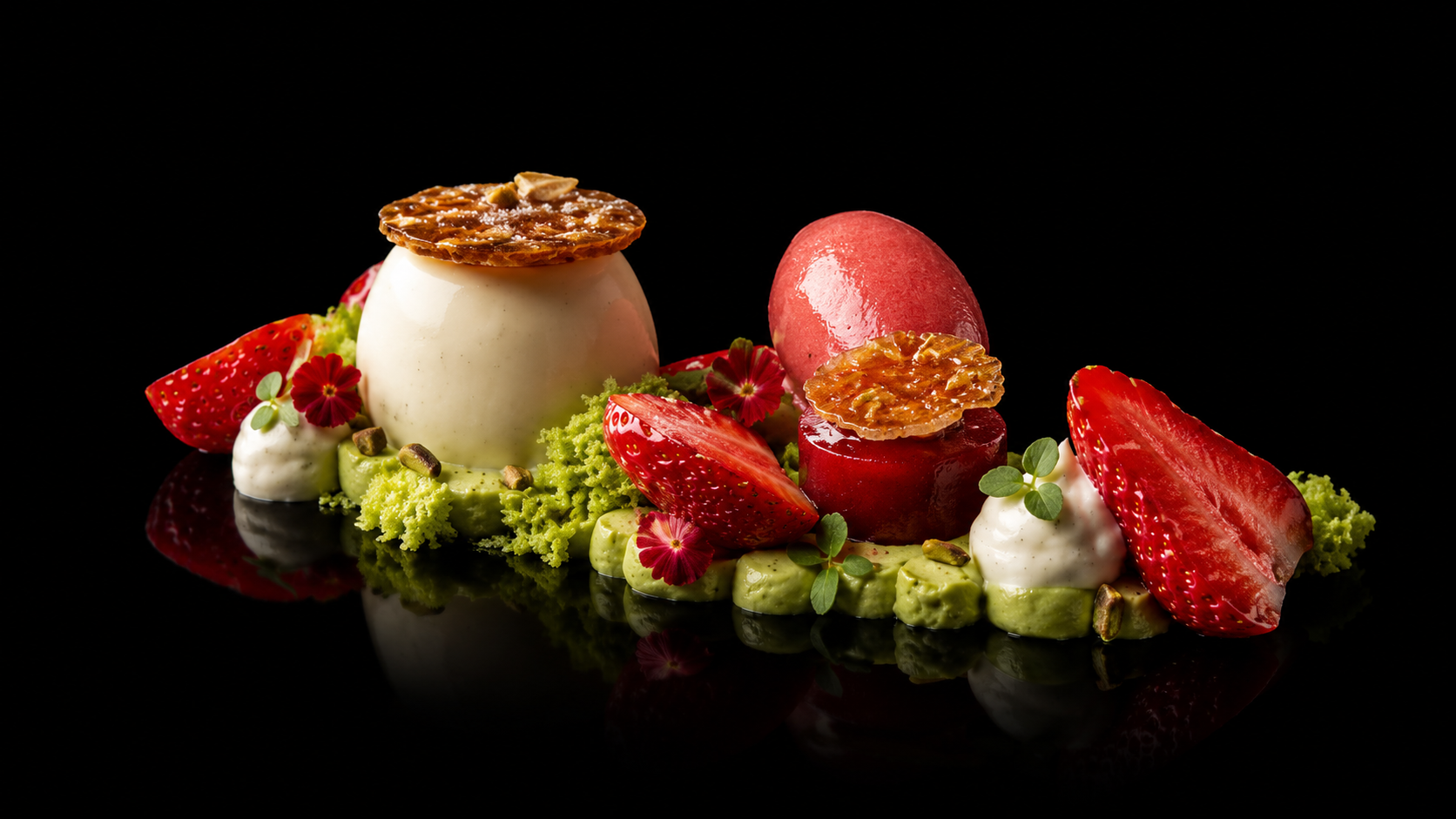 Assiette de dessert sophistiqué avec panna cotta, fraises, pistaches, croustillant aux noix, petits fruits et feuilles vertes décoratives, sur fond noir.