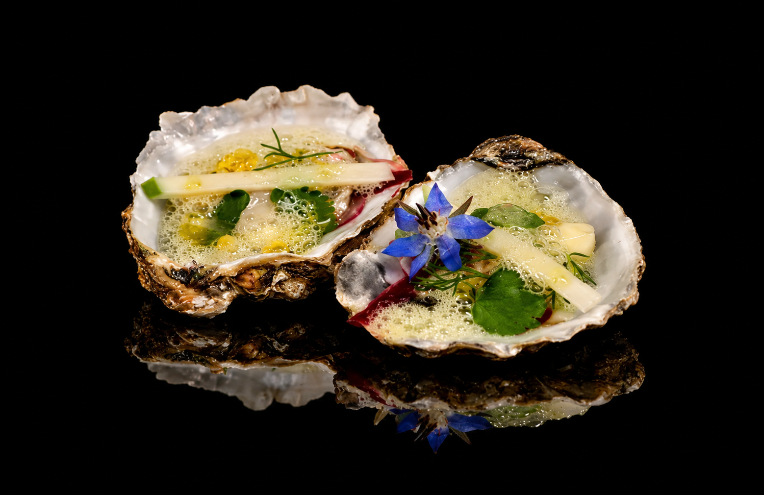 Huitres garnies de beurre aux herbes, citron, fleurs comestibles et herbes aromatiques, sur fond noir.