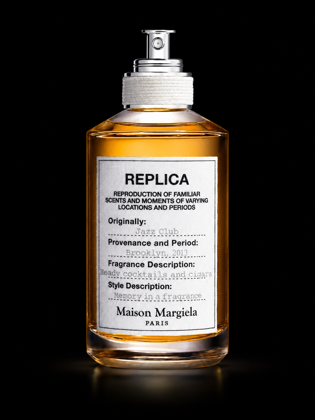 Flacon de parfum avec étiquette qui indique la marque Majestic Paris, la description du parfum Réplica d'une fragrance rappelant les cocktails et cigares, et mentionne une origine à Brooklyn en 2013.