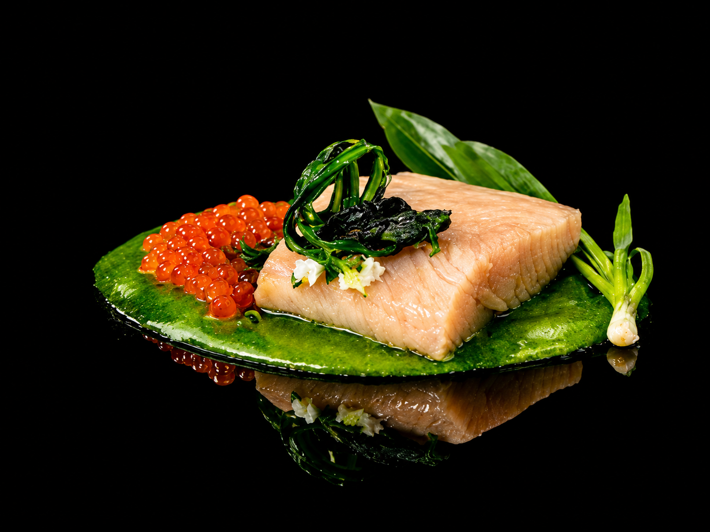 Un plat de sashimi avec du saumon, accompagné de œufs de poisson orange, de feuilles vertes et de garnitures vertes, présenté sur une assiette noire réfléchissante.