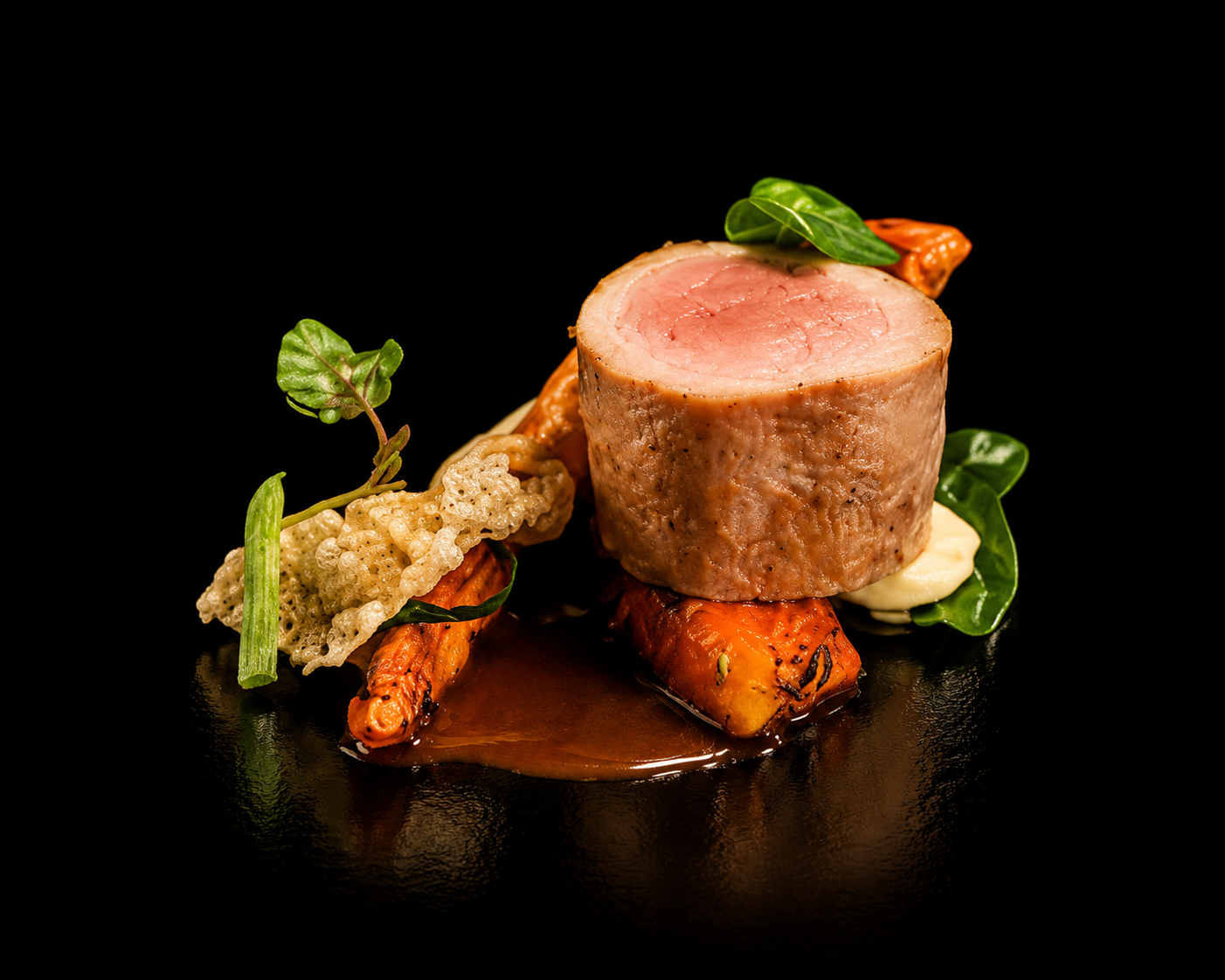 Filet mignon de porc avec accompagnements de légumes et sauce brune, présenté sur une assiette noire.