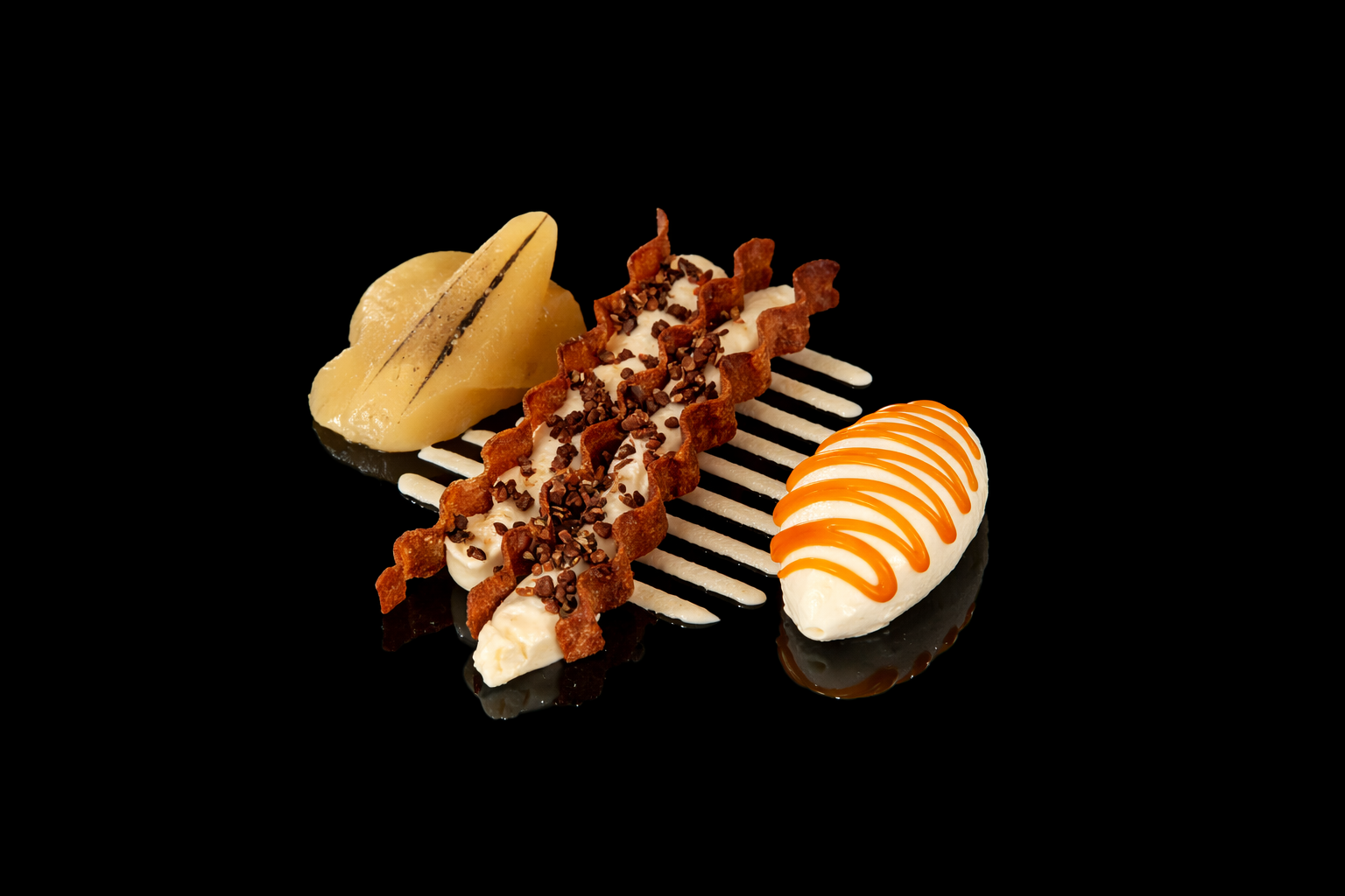 Assortiment de desserts pâtissiers avec poire, chantilly, caramel et sablé, présenté sur une surface noire