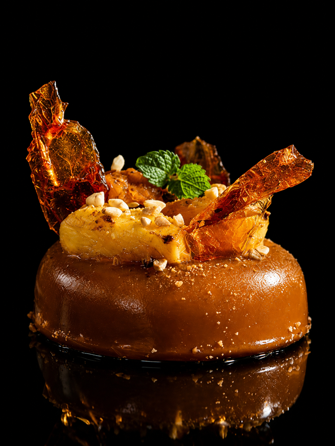 Dessert au caramel avec du fruit, des noix et une feuille de menthe