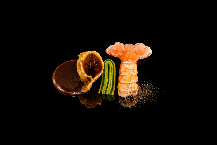 Un assortiment de plats gastronomiques avec une crevette, un morceau de concombre, un muffin ou une pâtisserie et une sauce au chocolat, présentation élégante sur fond noir.