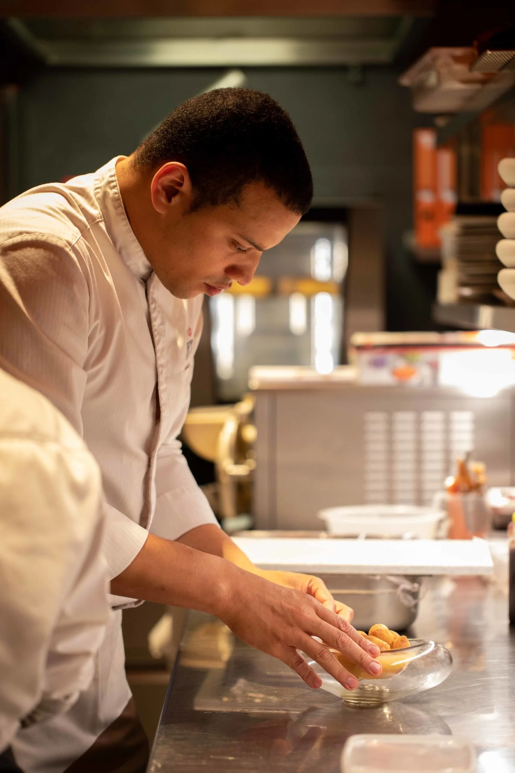 Un homme en uniforme de cuisine prépare de la nourriture dans une cuisine professionnelle.