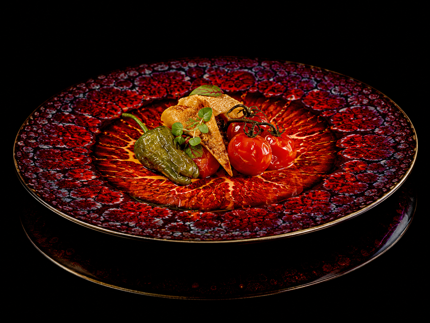 Plat de légumes grillés sur une assiette en verre à motifs rouges et noirs.