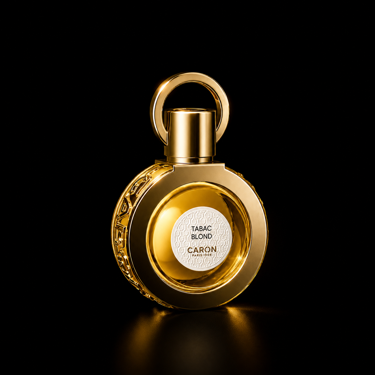 Flacon de parfum doré avec une étiquette blanche portant le texte « Tabac Blond » et « Caron Paris 1904 » sur fond noir