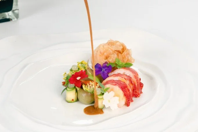 Assiette de sashimi de poisson avec des fleurs comestibles et une sauce versée dessus