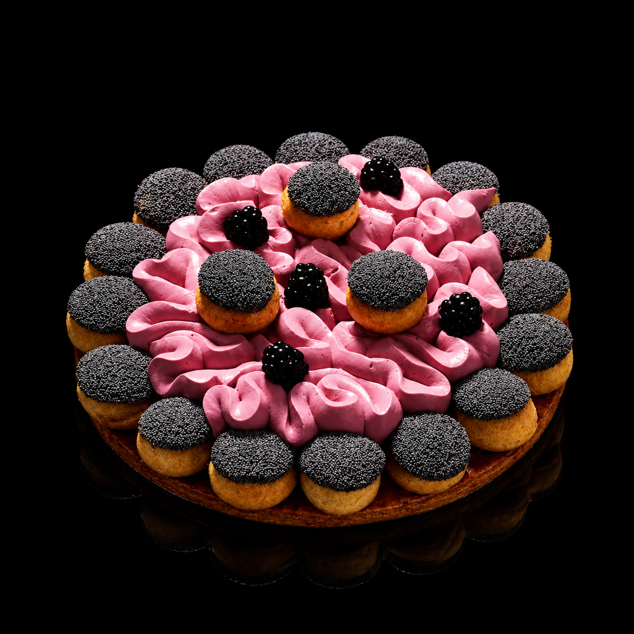 Gâteau rond décoré avec des petits choux recouverts de sucre noir, des glaçages roses en spirale, et des mûres noires, placé sur une base en bois noire.