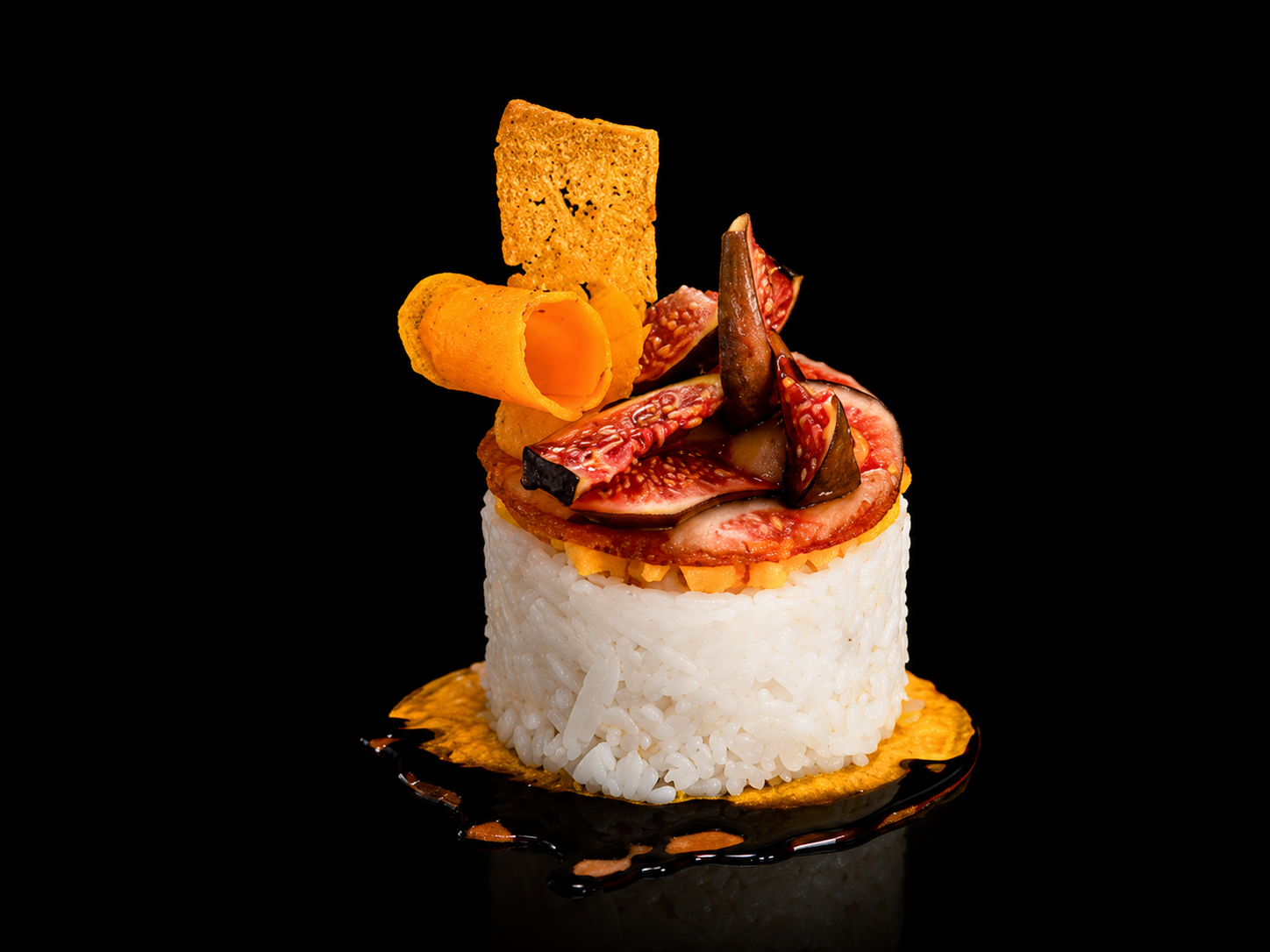 Présentation d'un sushi composé de riz blanc, de figs, de jambon, de chips de fromages, de tranches de viande, et d'un cracker, sur une surface noire