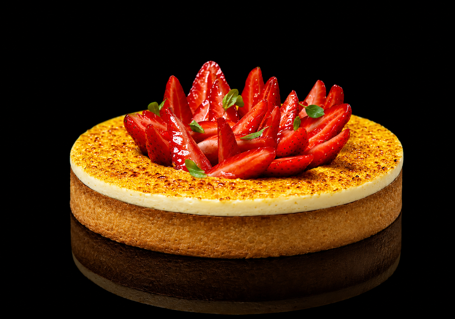 Gâteau aux fraises sur fond noir, avec une base biscuitée, une couche de crème et des fraises coupées décoratives sur le dessus.