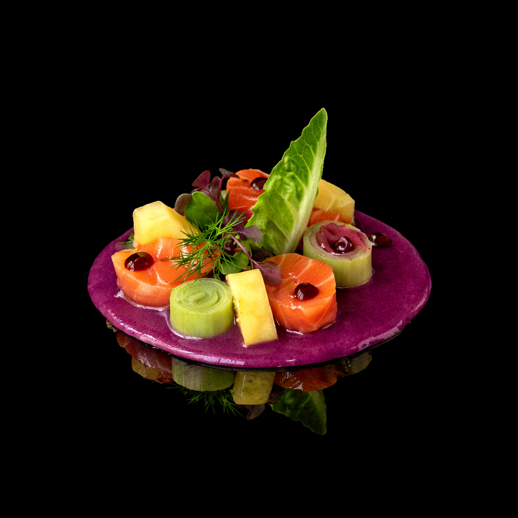 Une assiette de ceviche avec du poisson cru, des légumes et des herbes sur une plaque de pierre violette, fond noir.