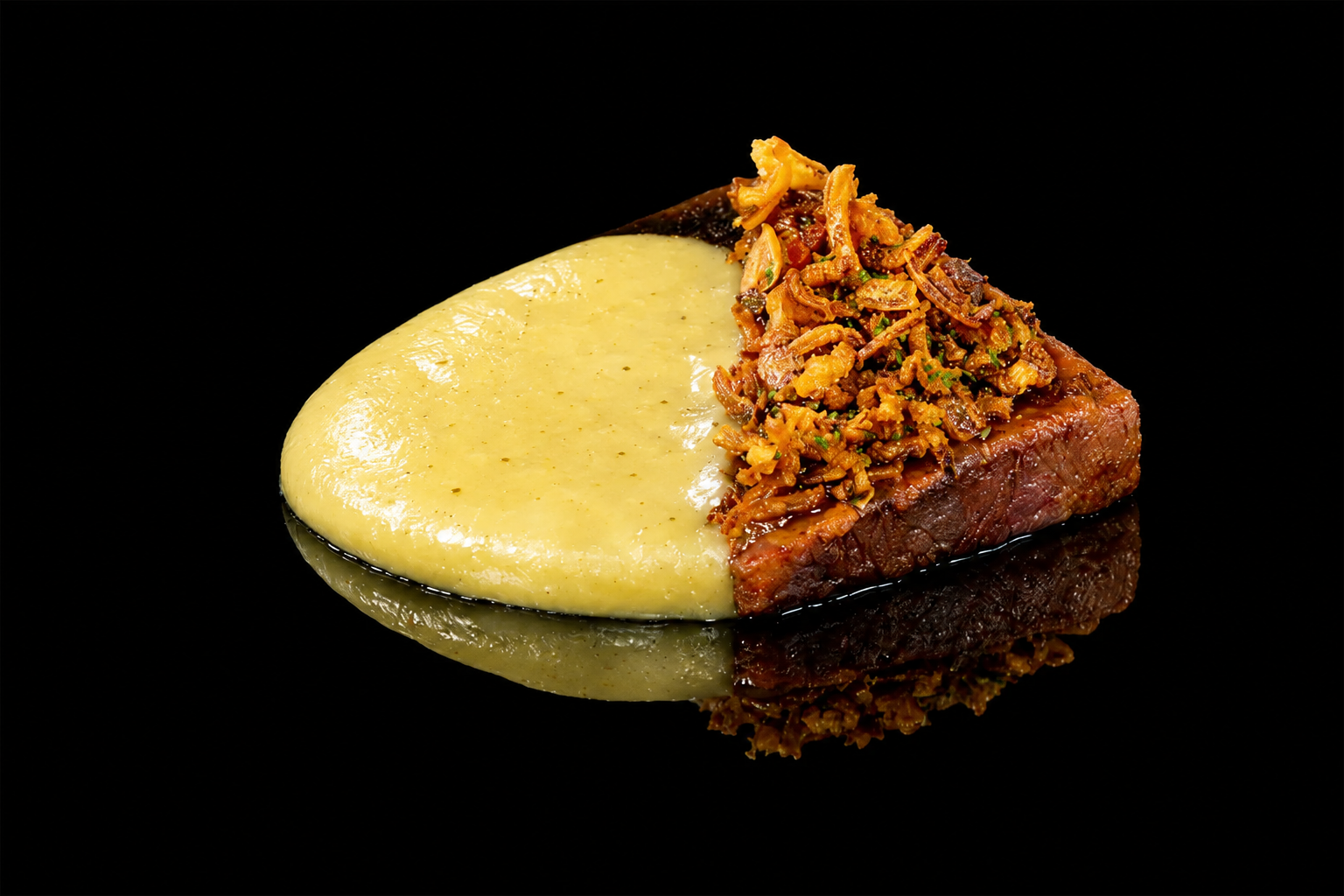Une portion de viande avec une croûte, accompagnée de purée de pommes de terre et d'une garniture de légumes sautés, sur fond noir.