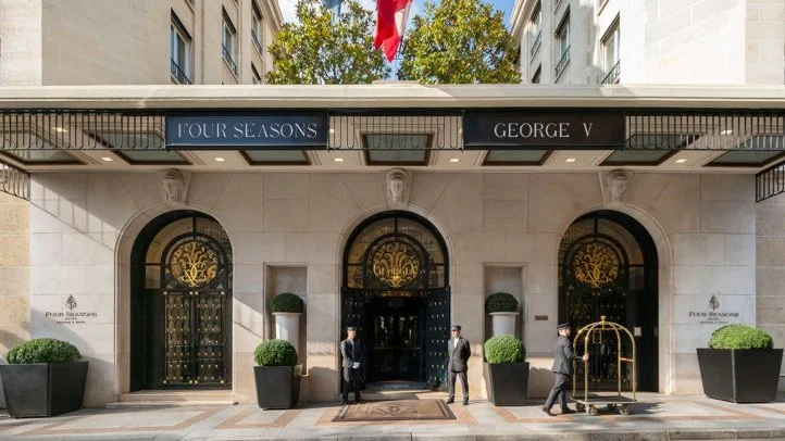 Façade de l'hôtel Four Seasons George V avec trois portes en verre et deux gardes devant l'entrée.
