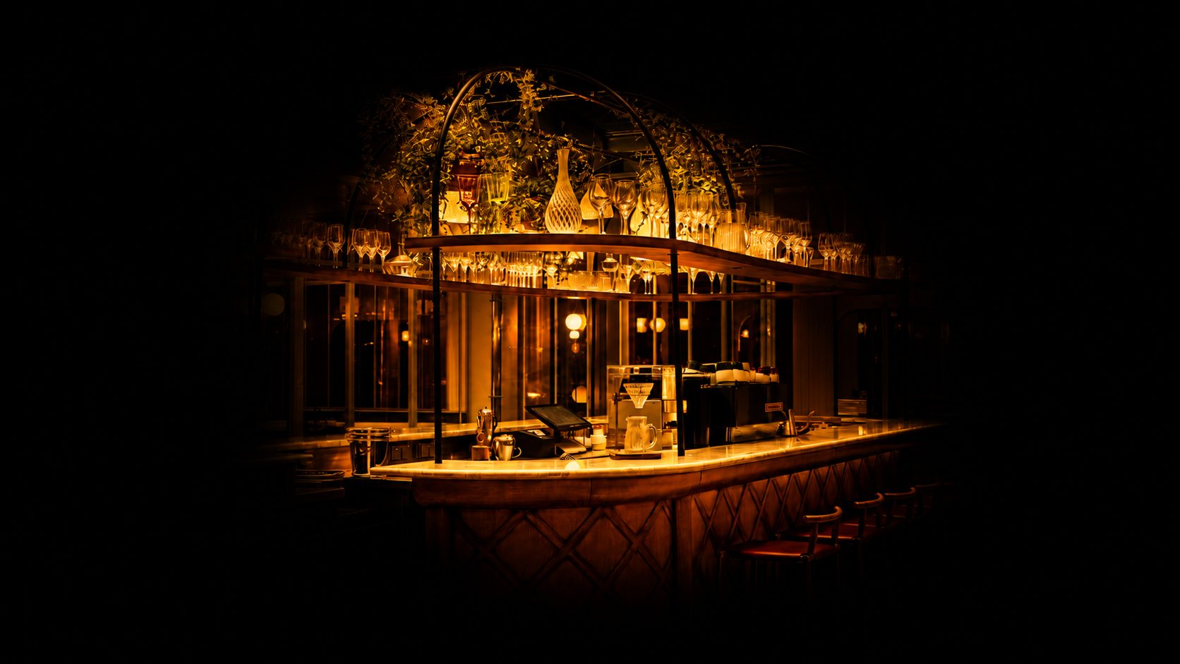 Un bar élégant avec un éclairage chaud, des verres à cocktail et une machine à café sur le comptoir.