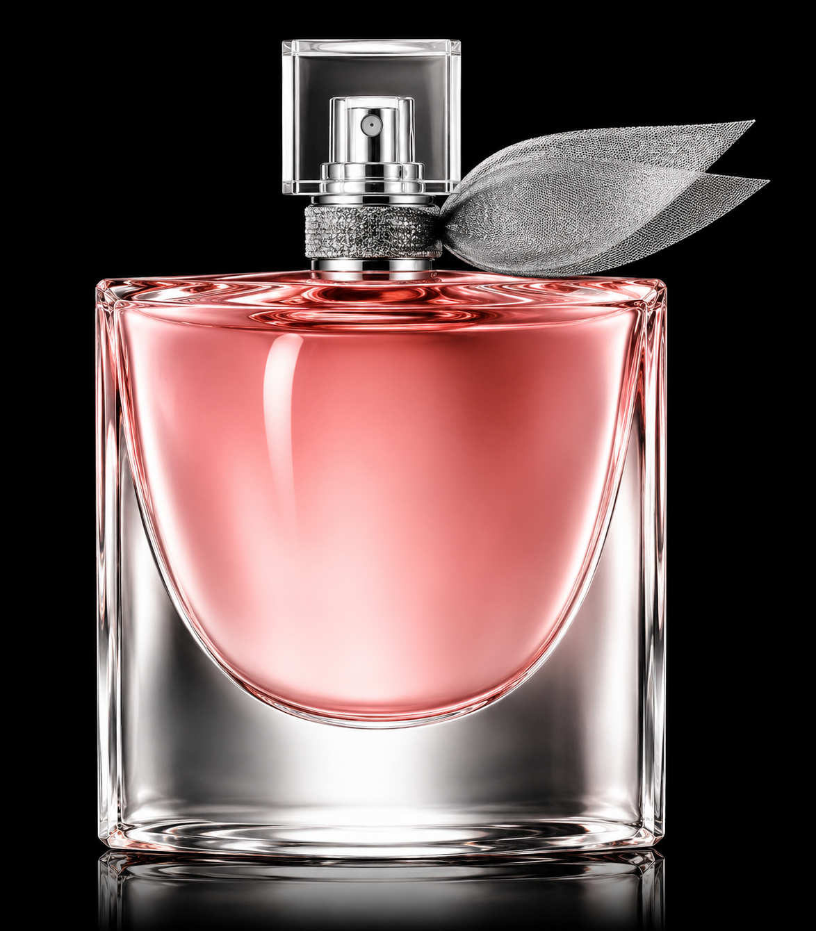 Flacon de parfum rose dans un contenant en verre transparent avec un bouchon en plastique transparent, décoré d'une feuille en tissu argentée, sur un fond noir.