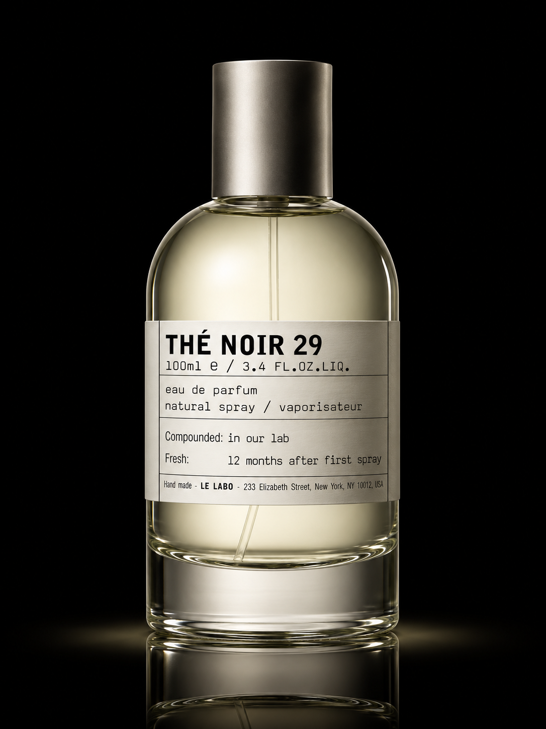 Bouteille de parfum transparent avec un liquide clair, étiquette blanche avec texte noir indiquant 'Thé Noir 29', contenant 100ml, produit par Le Labo, positionnée contre un fond noir.