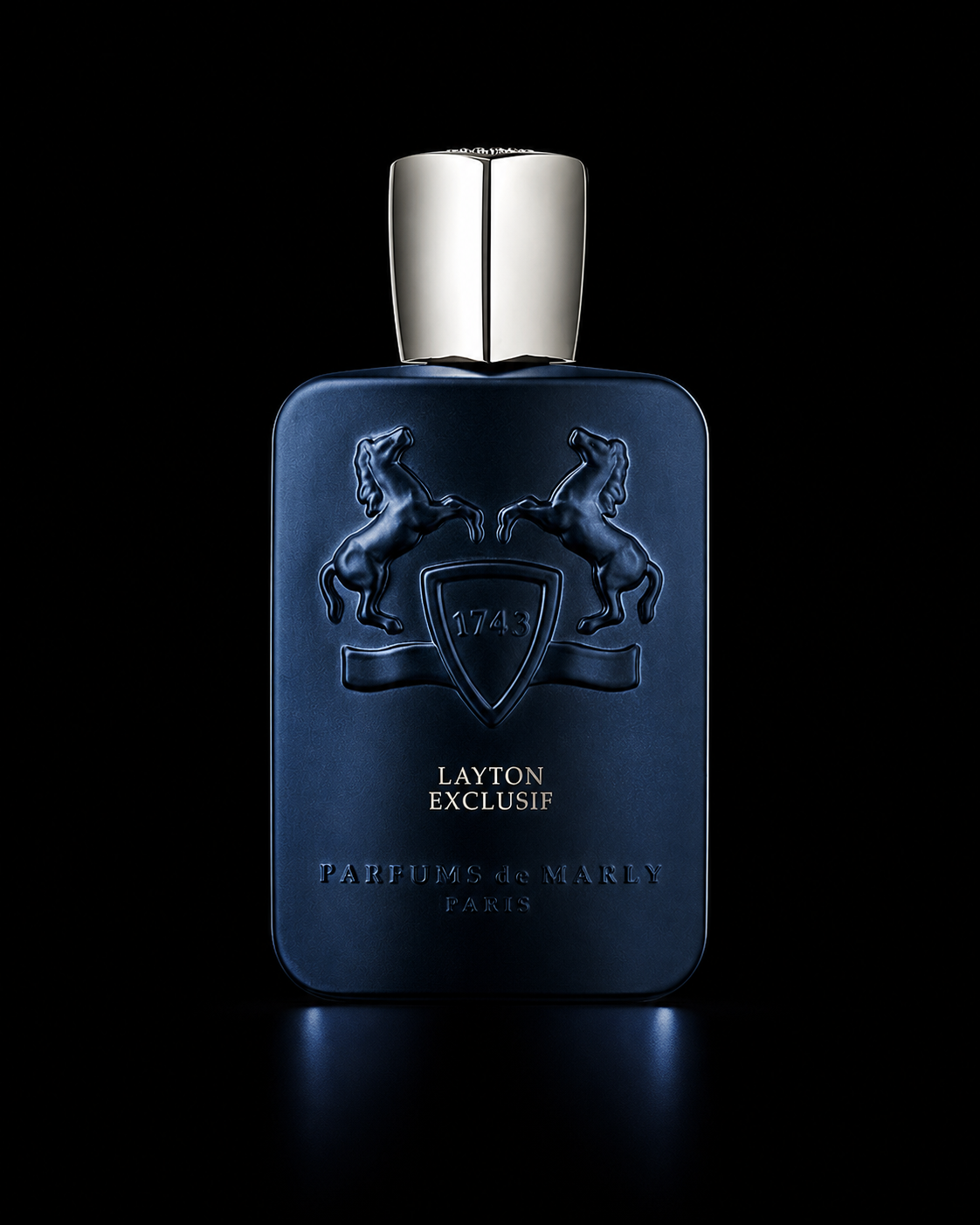 Flacon de parfum bleu foncé avec deux chevaux en relief et une plaque portant l'année 1743, marqué "Layton Exquis" et "Parfums de Marly, Paris", sur fond noir.