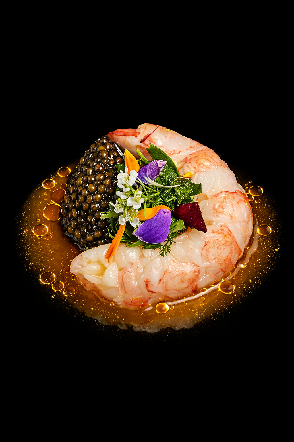 Gambero e caviale di colore nero con contorno di aroma di olio e fiori eduli