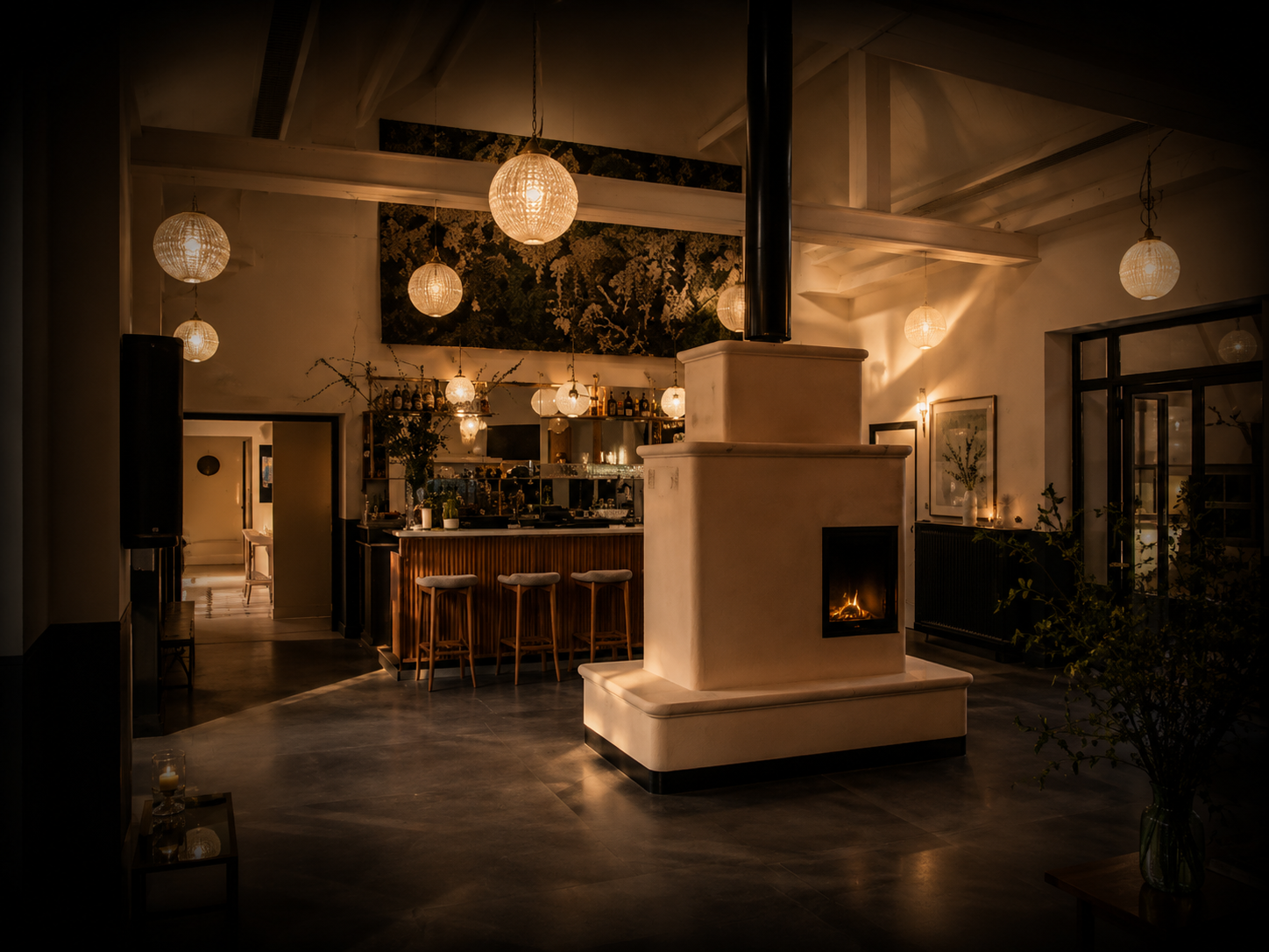 Intérieur chaleureux d'un bar ou restaurant avec éclairage tamisé, lampes en papier, cheminée allumée, comptoir en bois, et décor floral sur un mur.
