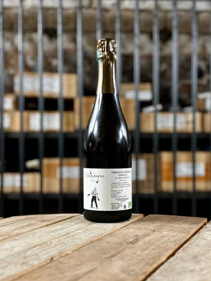 Une bouteille de champagne noir avec une étiquette blanche sur une table en bois, arrière-plan d'étagères avec des caisses en bois.