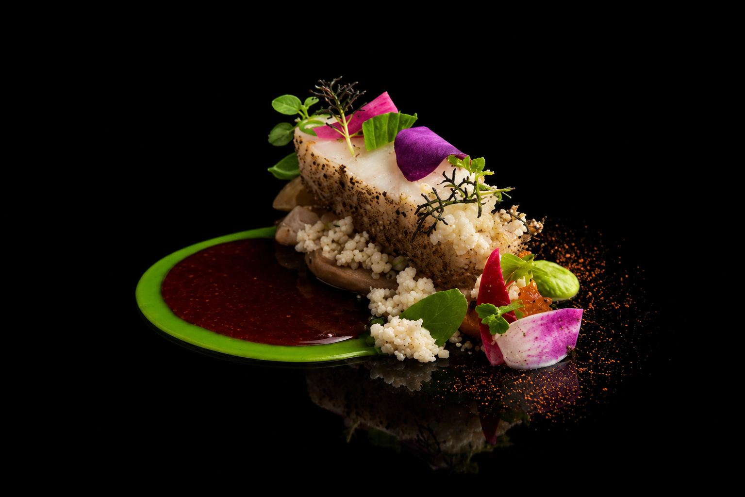 Assiette gastronomique avec un poisson, garnitures végétales, et sauce, présentée sur un fond noir.