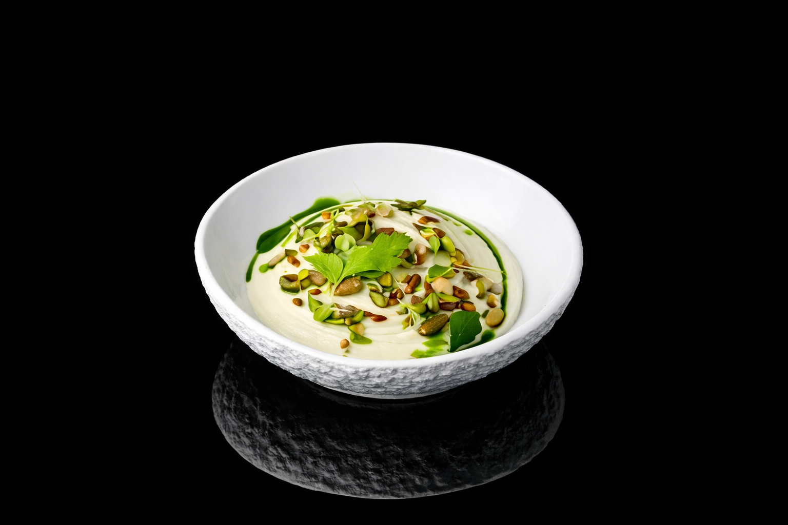 Plat de yaourt ou pudding avec des graines et des feuilles vertes sur une assiette blanche, fond noir.