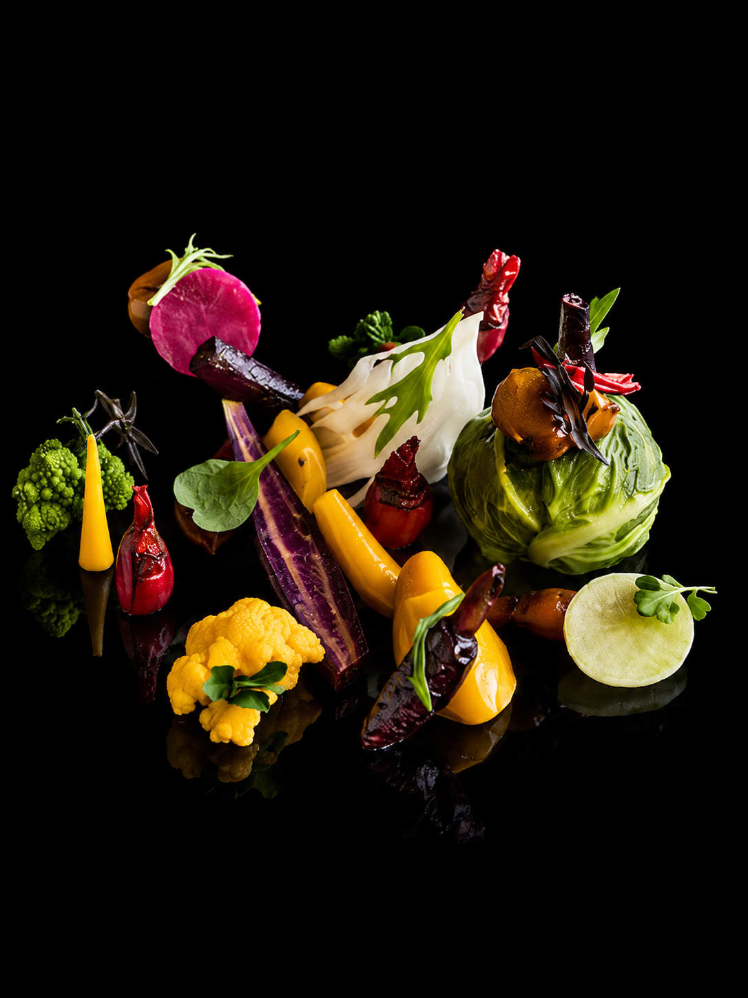 Assiette de légumes colorés et artistiques sur fond noir.