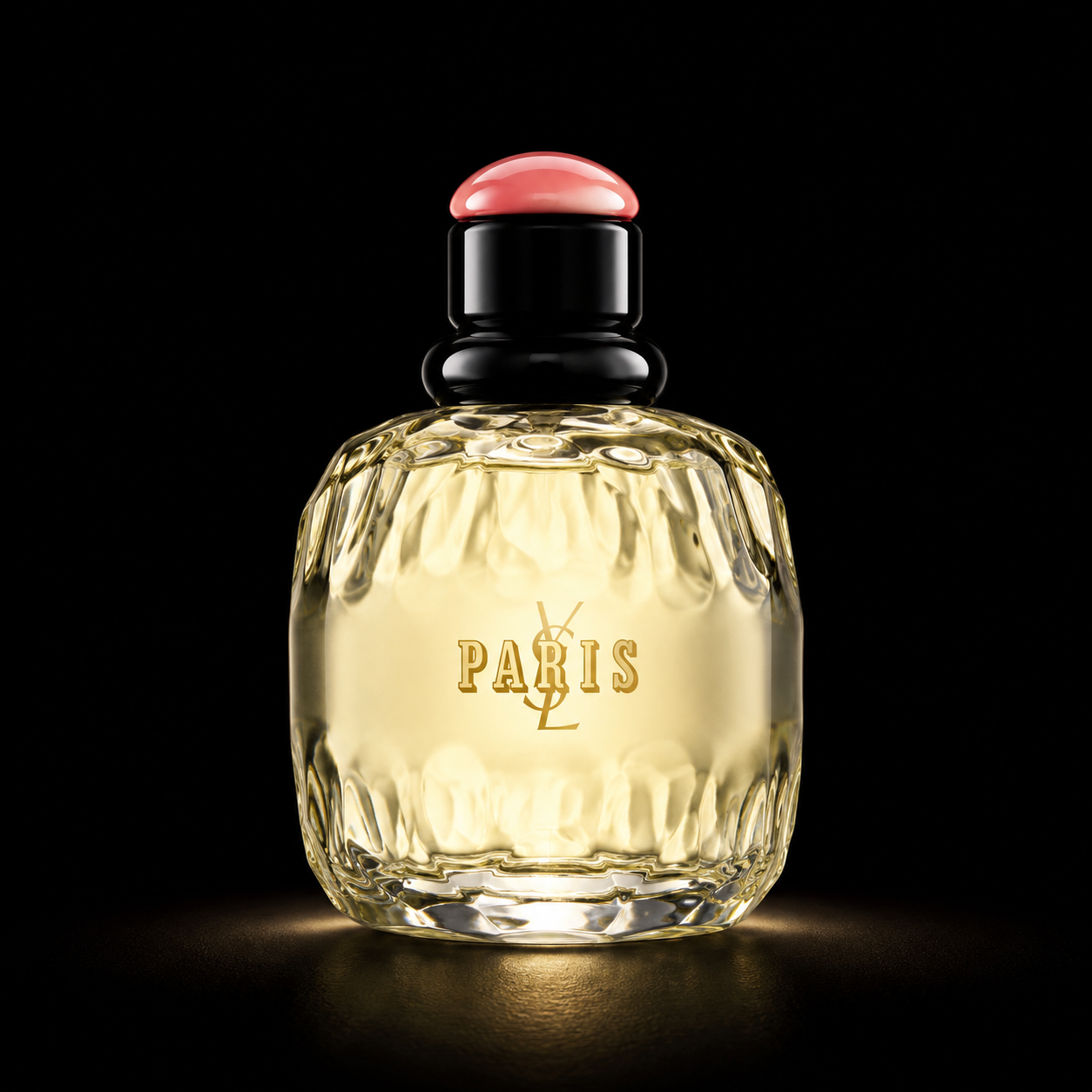 Flacon de parfum en verre orné d'une inscription "Paris" et d'un logo Yves Saint Laurent, avec un bouchon noir et un sommet rose, sur fond noir.