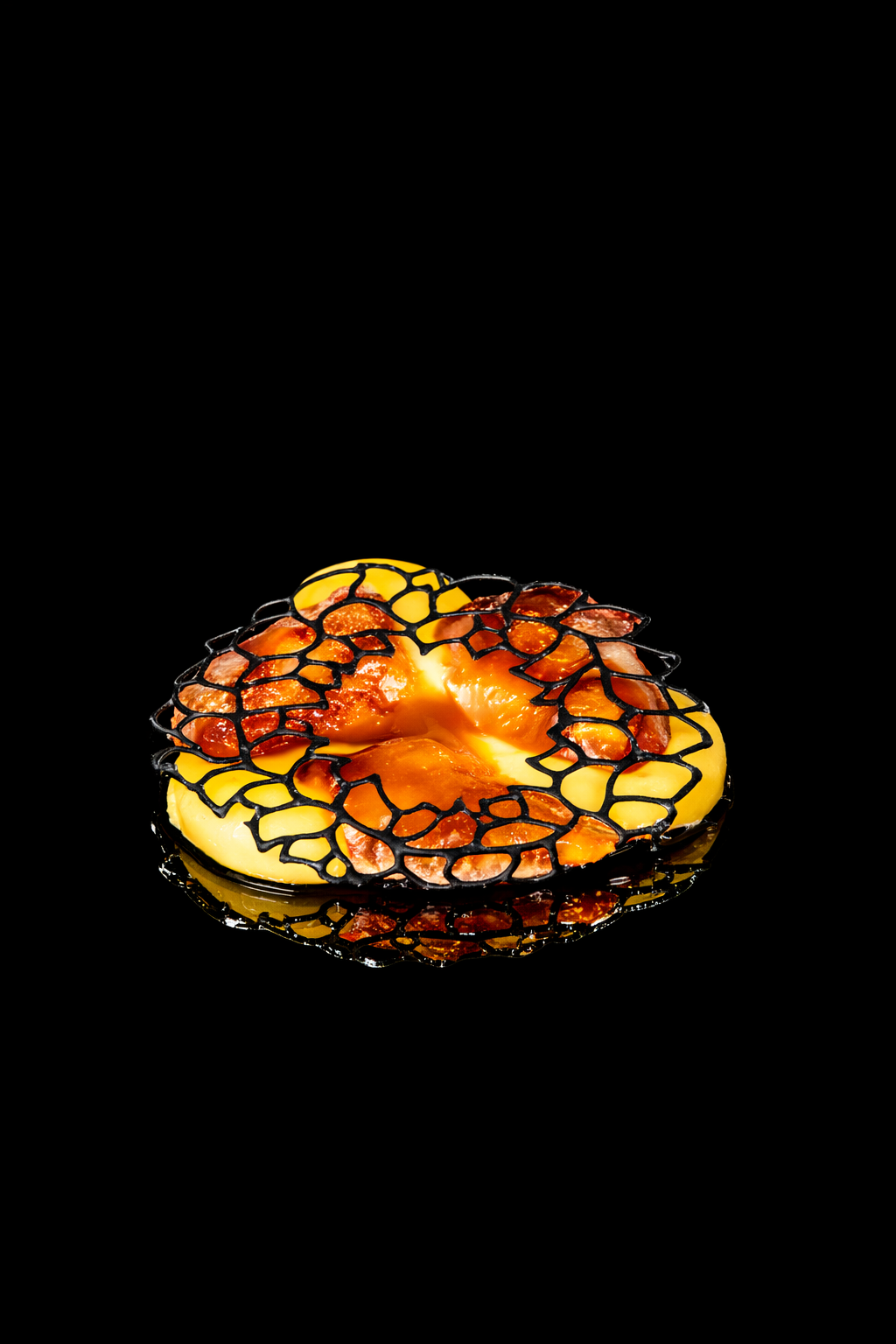 gâteau en forme de flamme avec une structure en forme de filets noirs, décoré avec des morceaux de bacon ou jambon, posé sur une surface noire